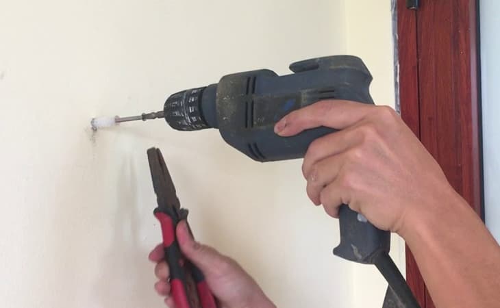 Khoan lỗ trên tường bằng mũi khoan tường kích thước phù hợp để đóng nở nhựa và bắt vít.
